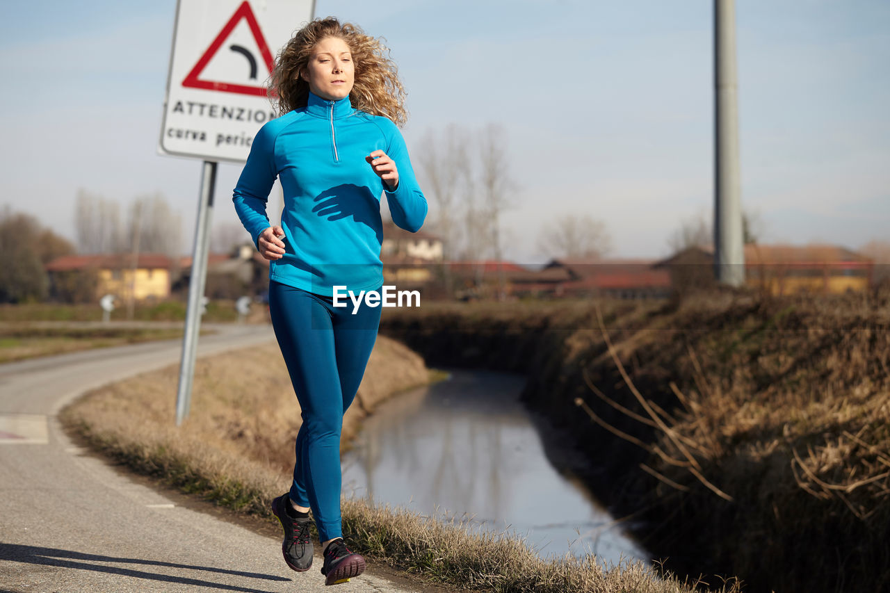 Woman running on road against sky