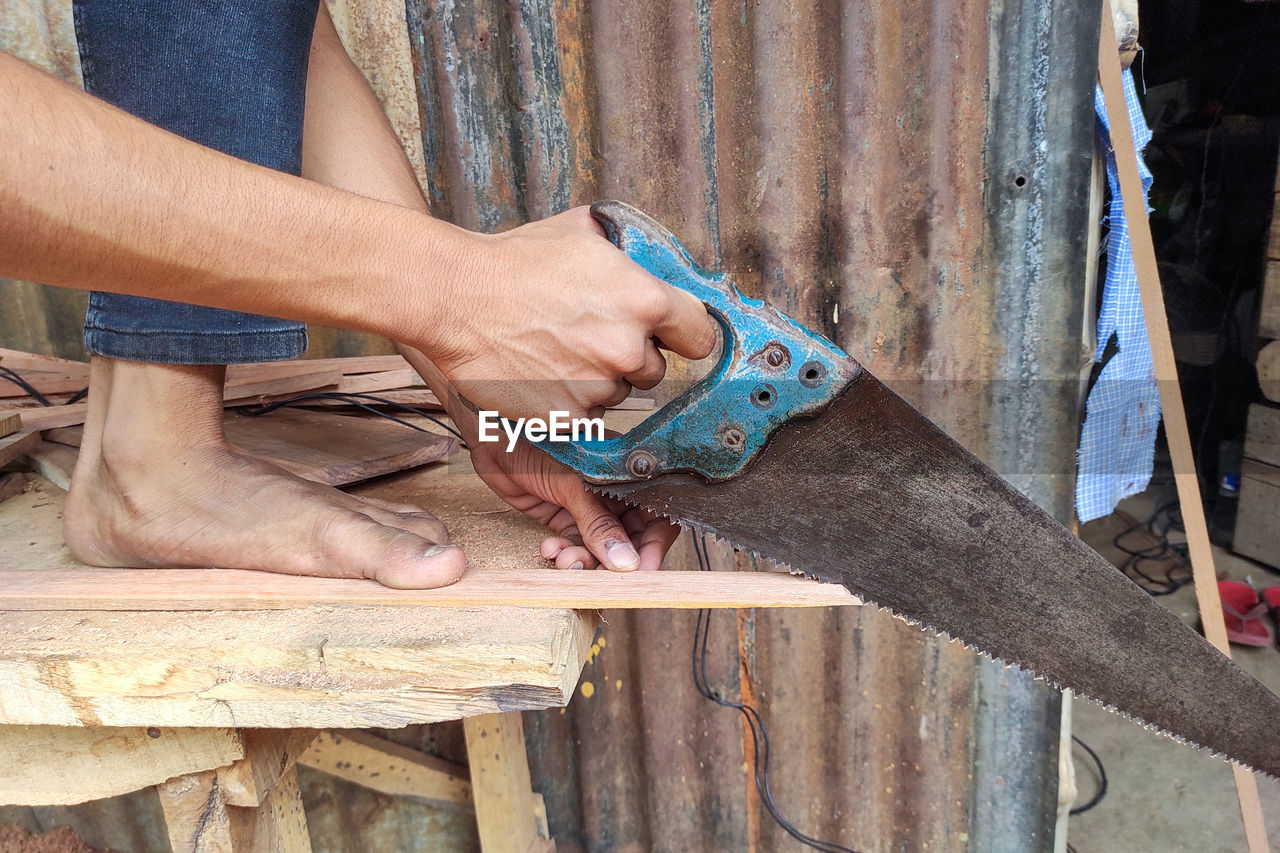 A carpenter working manually with a hand saw on a wooden background