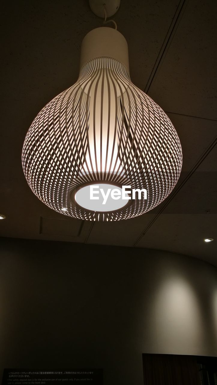 Low angle view of illuminated electric lamp hanging at home