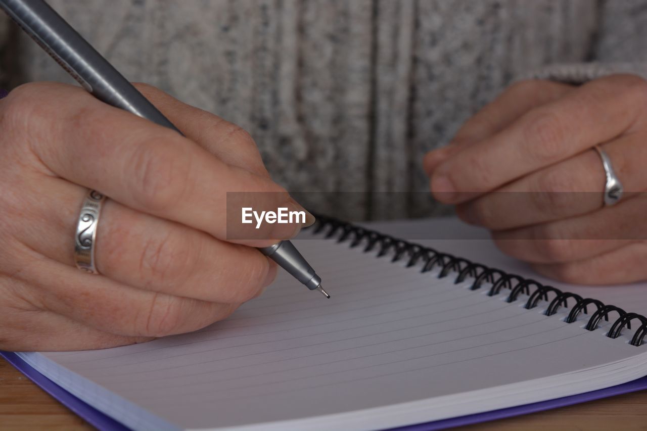 CLOSE-UP OF PERSON HAND HOLDING PAPER WITH TABLE