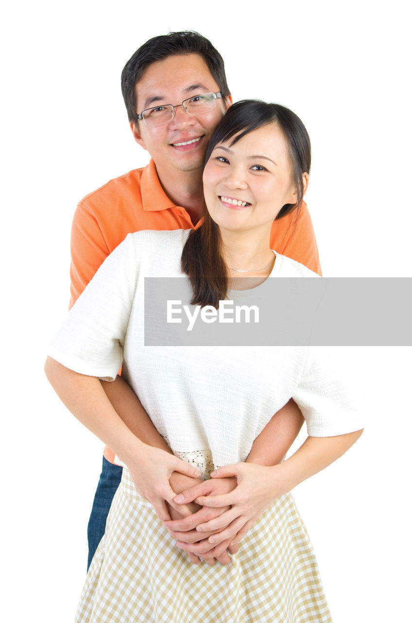 Portrait of smiling couple standing against white background