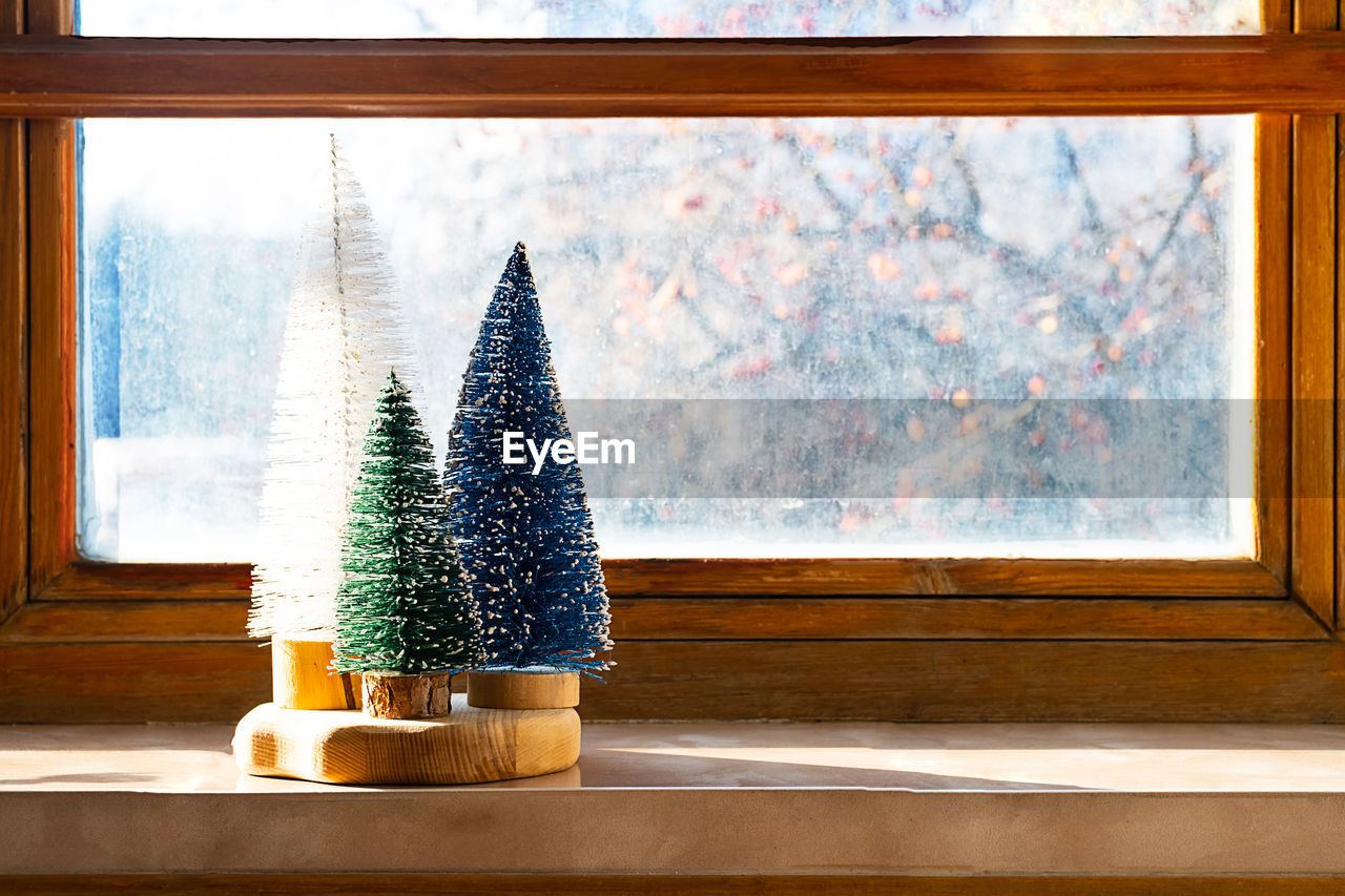 Colourful christmas trees on the window. trendy home decor for winter holidays.