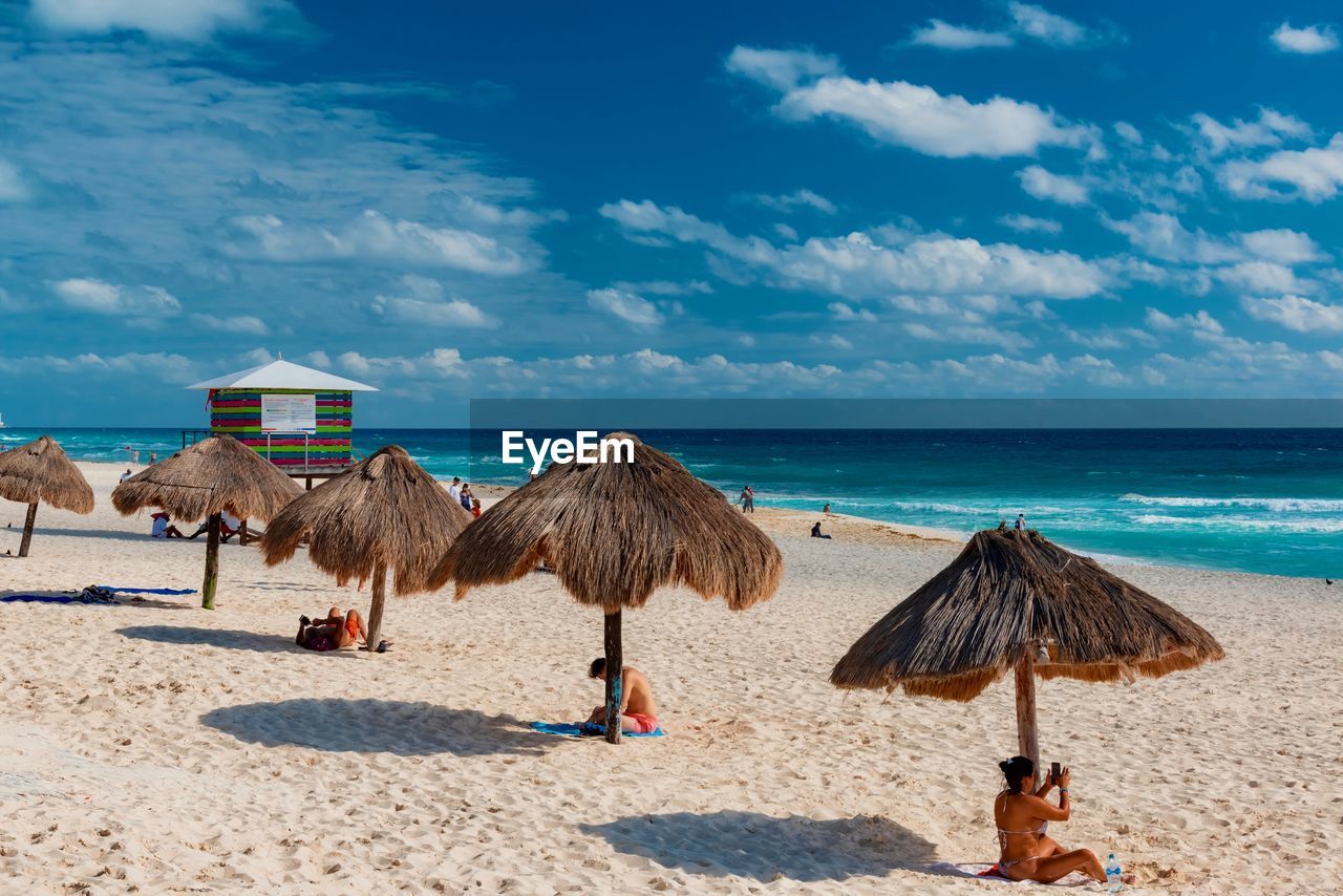 DECK CHAIRS ON BEACH AGAINST SKY