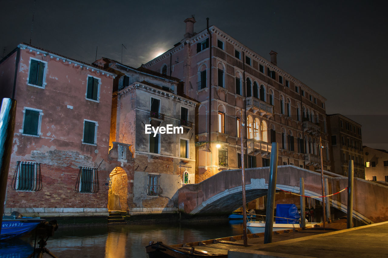 Canal by illuminated buildings against sky at night