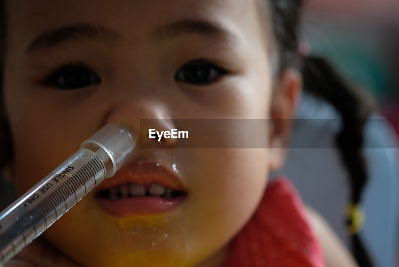 Close-up portrait of girl with syringe in nose