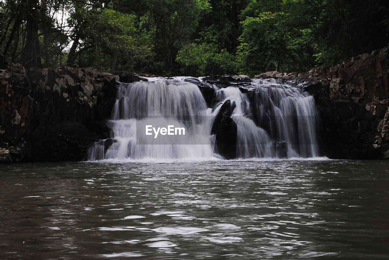 VIEW OF WATERFALL WITH TREES IN BACKGROUND