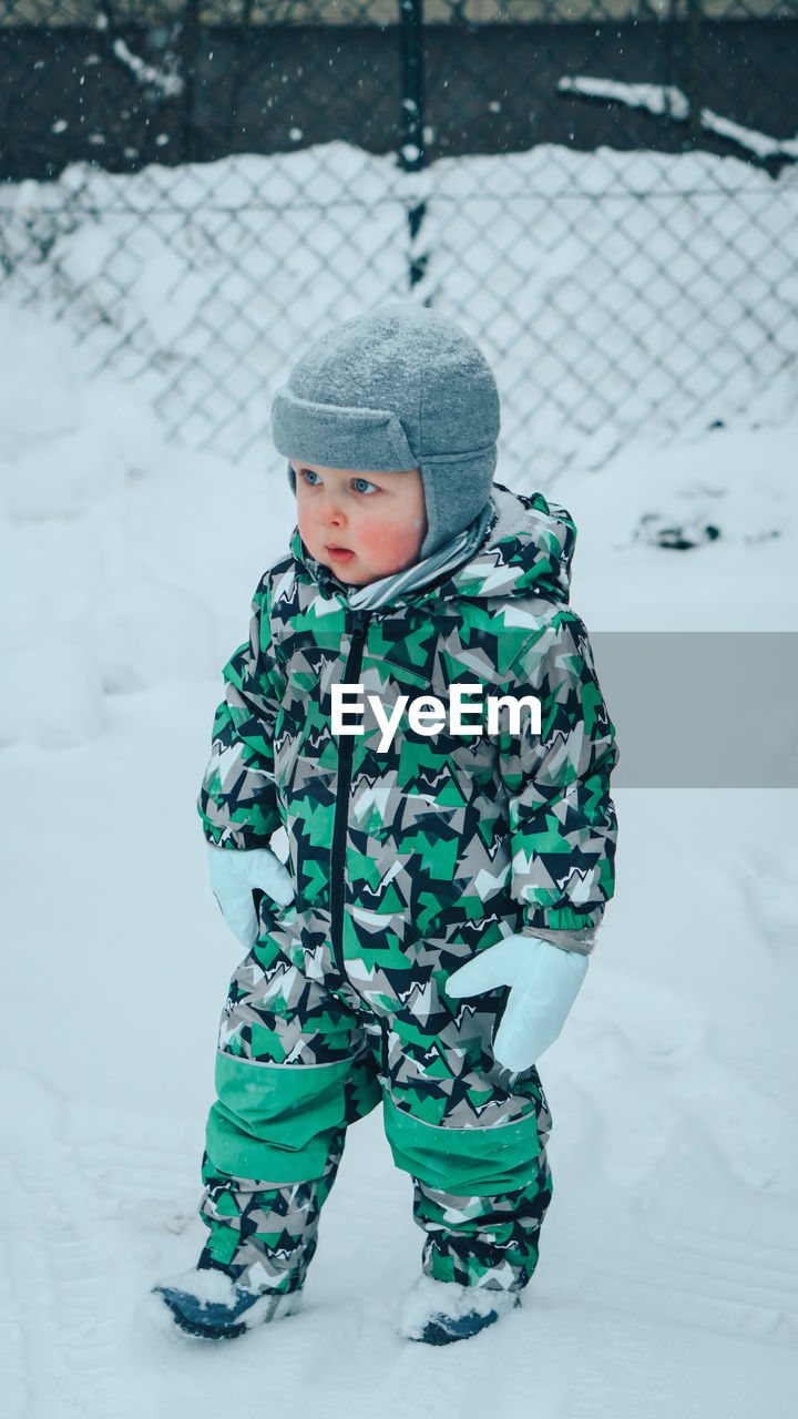 Cute boy in snow on field during winter