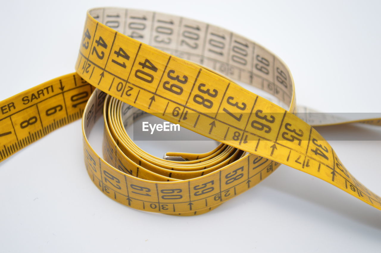 High angle view of measuring tape against white background