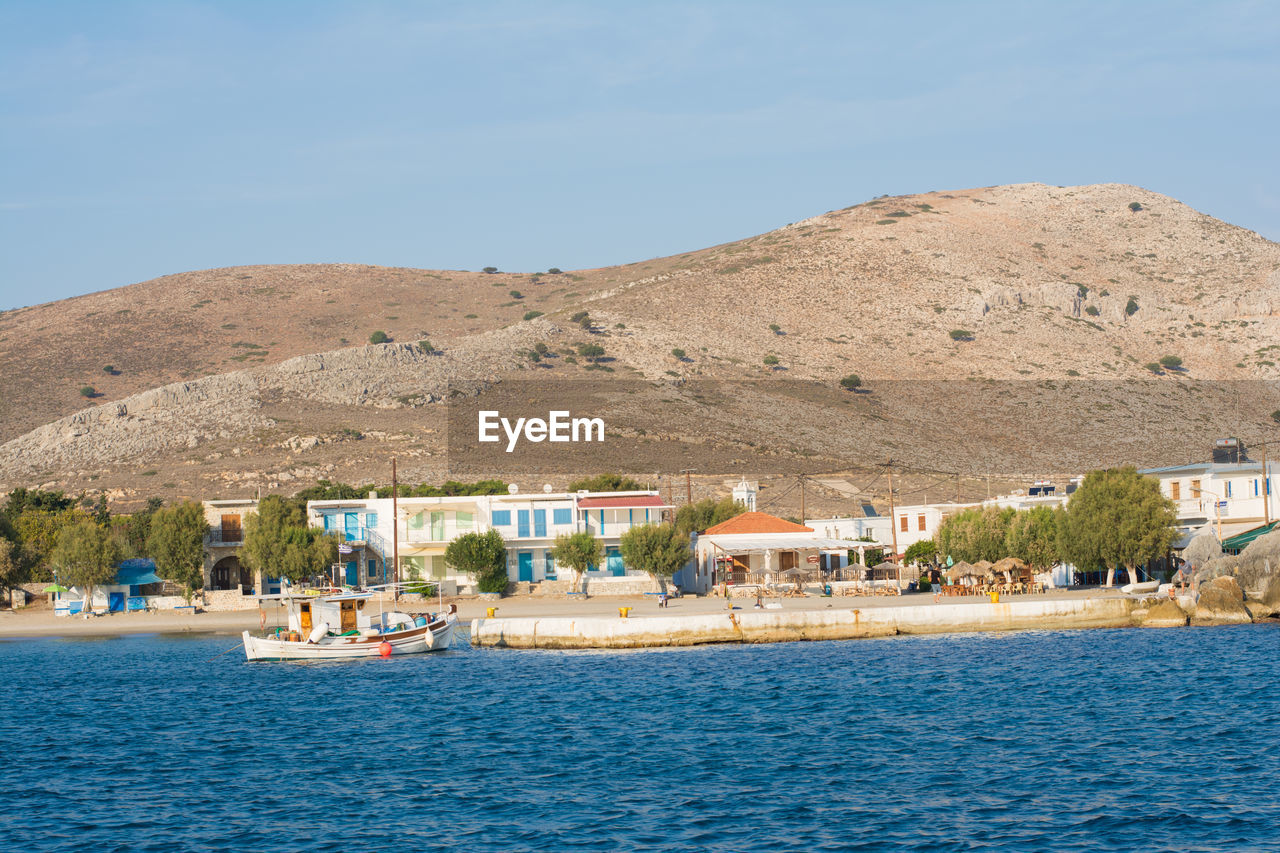 Buildings by sea against sky