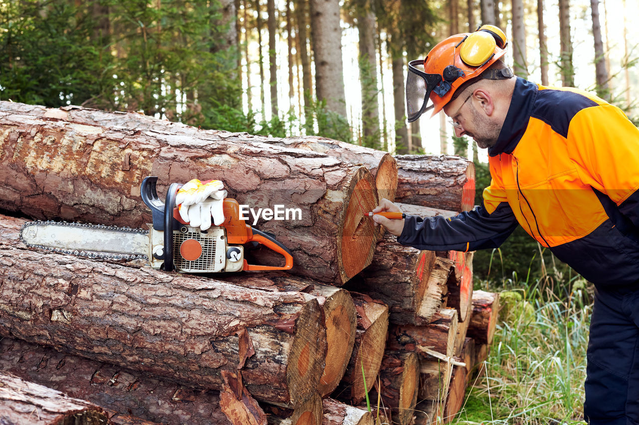 Professional lumberjack with protective workwear and chainsaw working in a forest