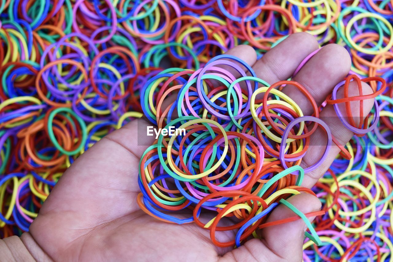 Cropped hand of woman holding multi colored rubber bands