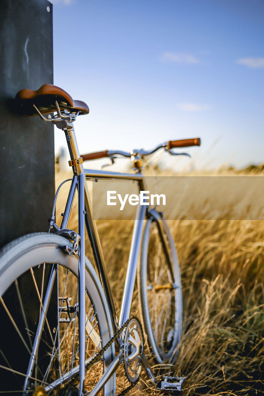 Bicycle on golden field against sky during sunset