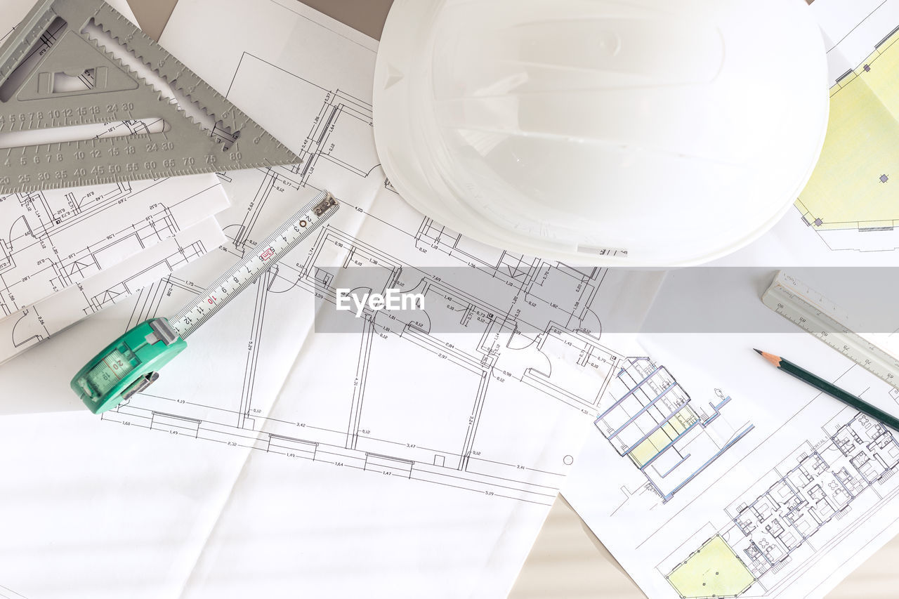 Architecture plans and contractor supplies on desk. top view