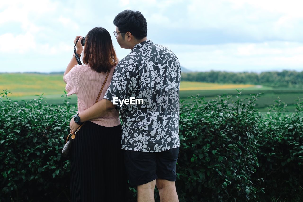 Rear view of couple photographing against sky