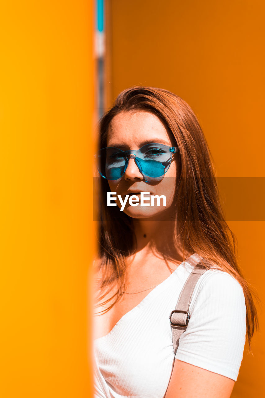 Portrait of beautiful woman standing against orange wall