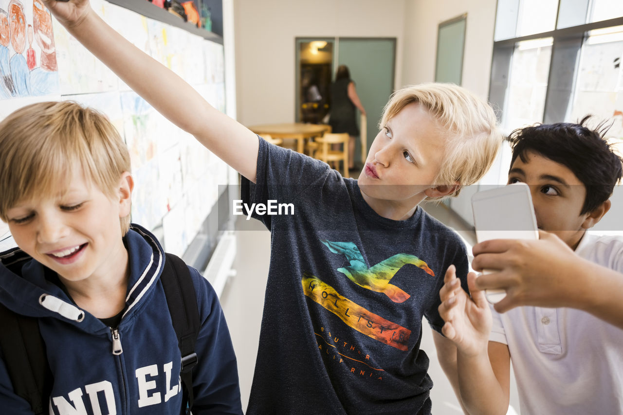 Boys taking selfie in corridor of school