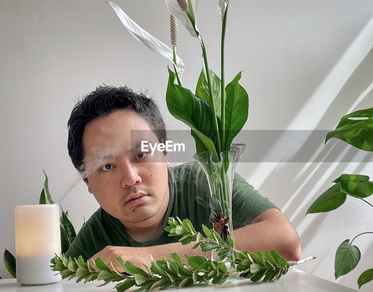 Young asian man with aroma diffuser, peace lilies and plants.