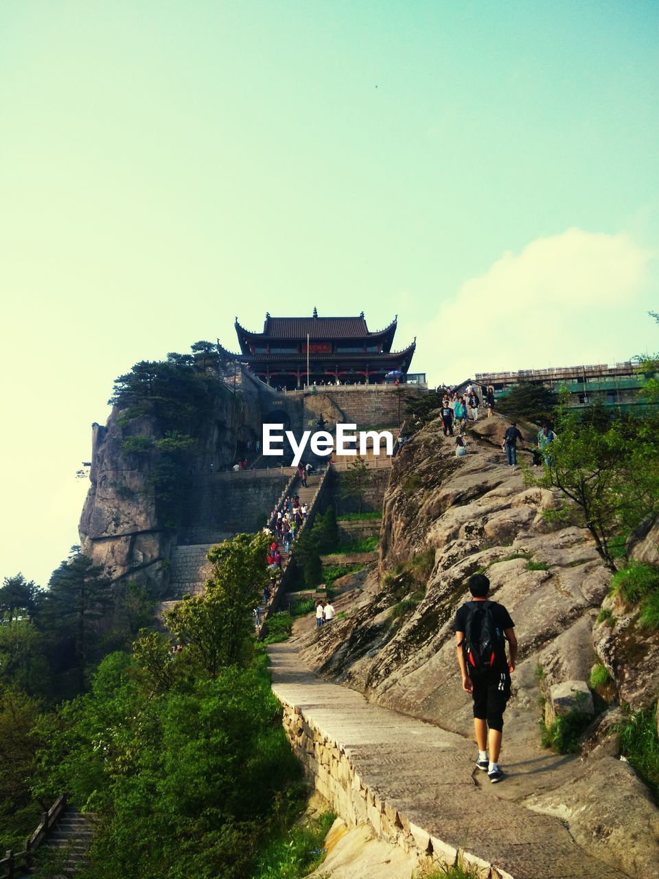 LOW ANGLE VIEW OF MAN STANDING ON TOP OF ROCK