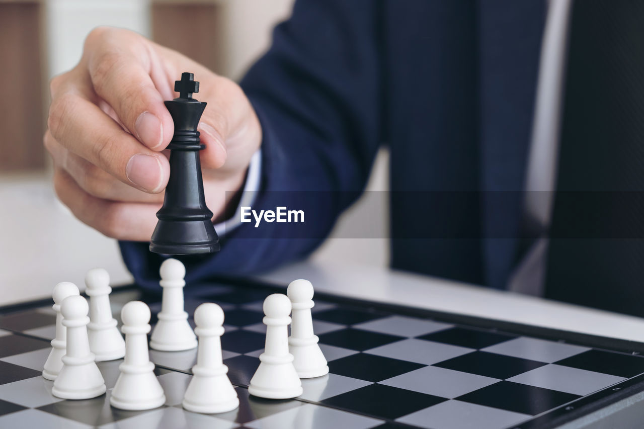 Midsection of businessman playing chess