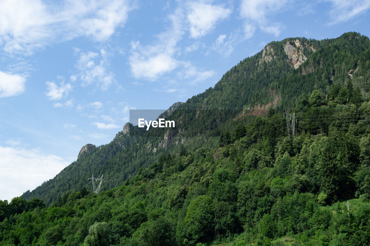 White clouds in a blue sky over a green hillside