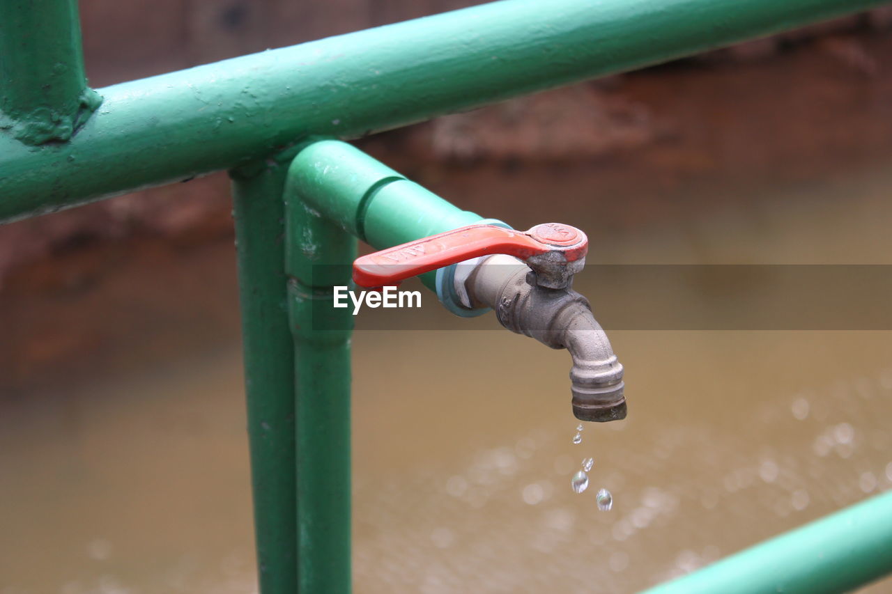 CLOSE-UP OF WATER DROPS ON PIPE AGAINST METAL