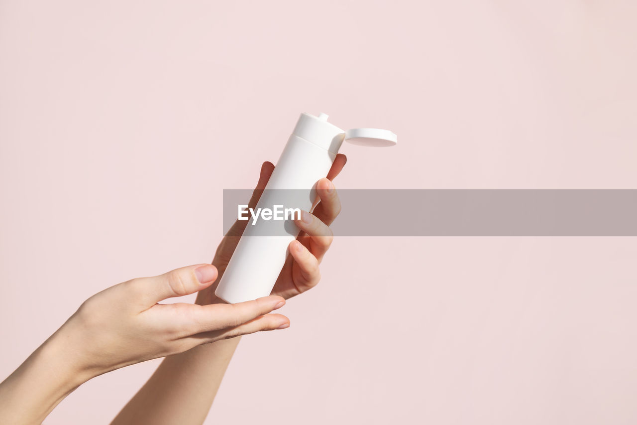 Young female hands holding blank white squeeze bottle plastic tube. mockup.