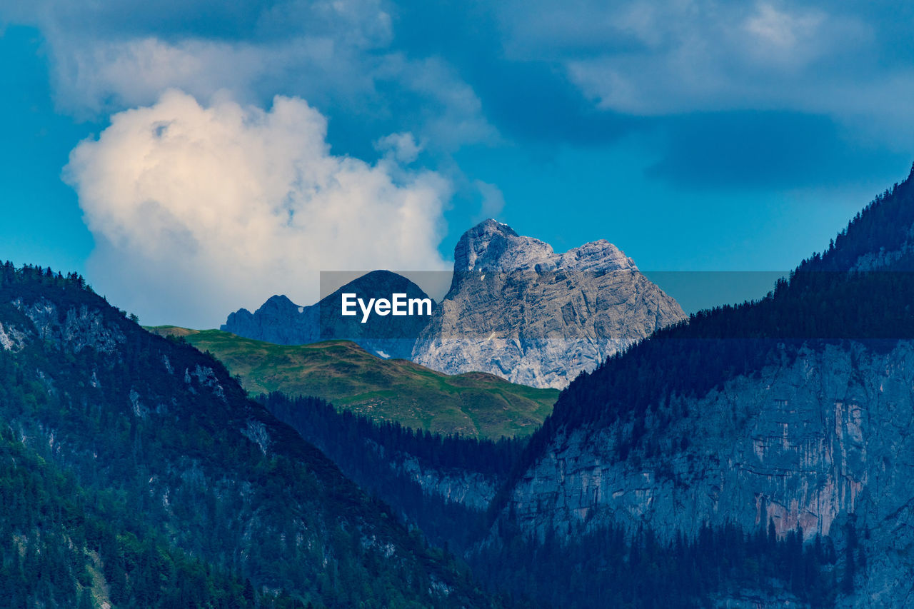 Low angle view of majestic mountains against cloudy sky