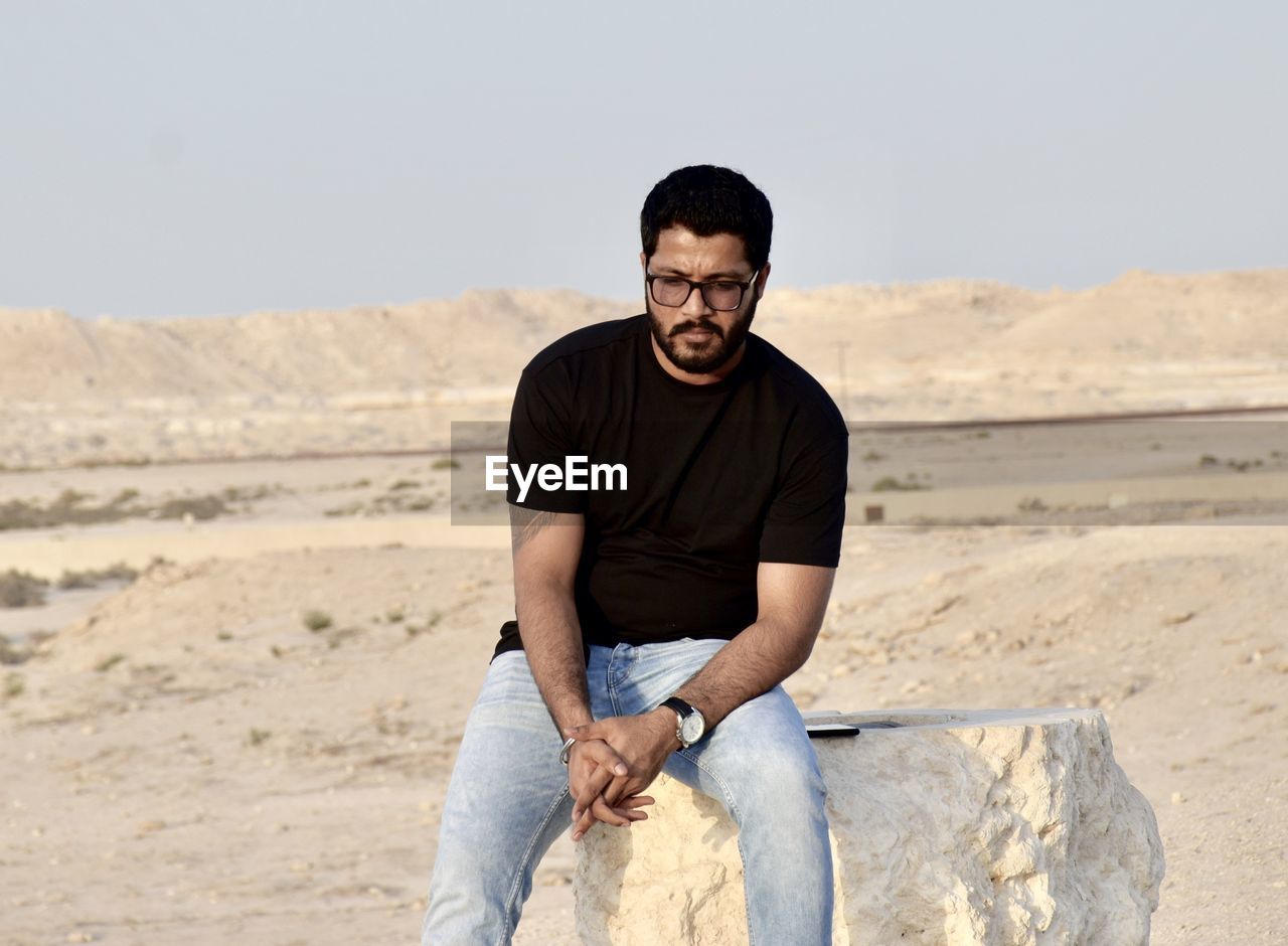 Full length of young man sitting on stone 