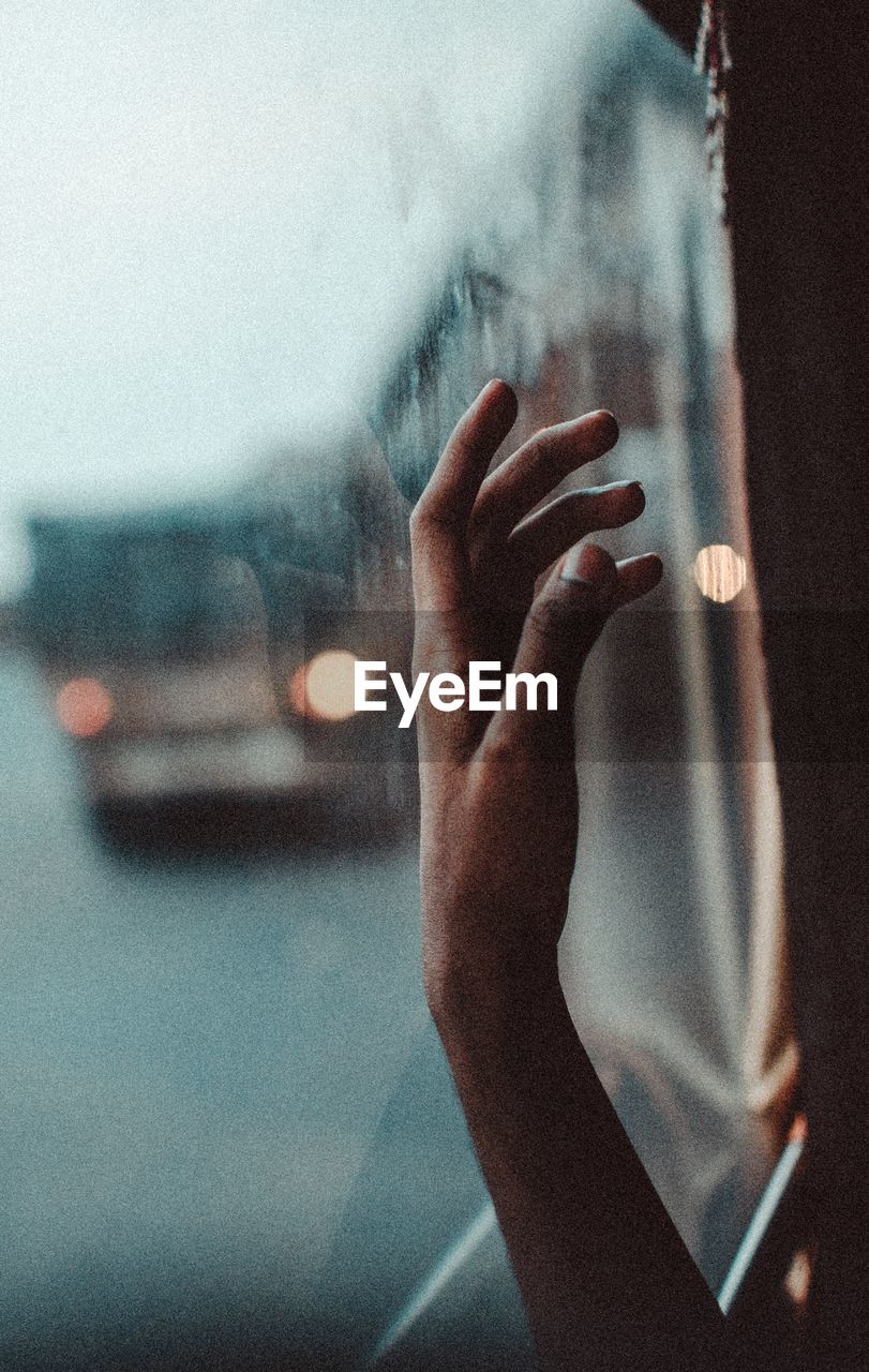 Cropped hand by window in bus