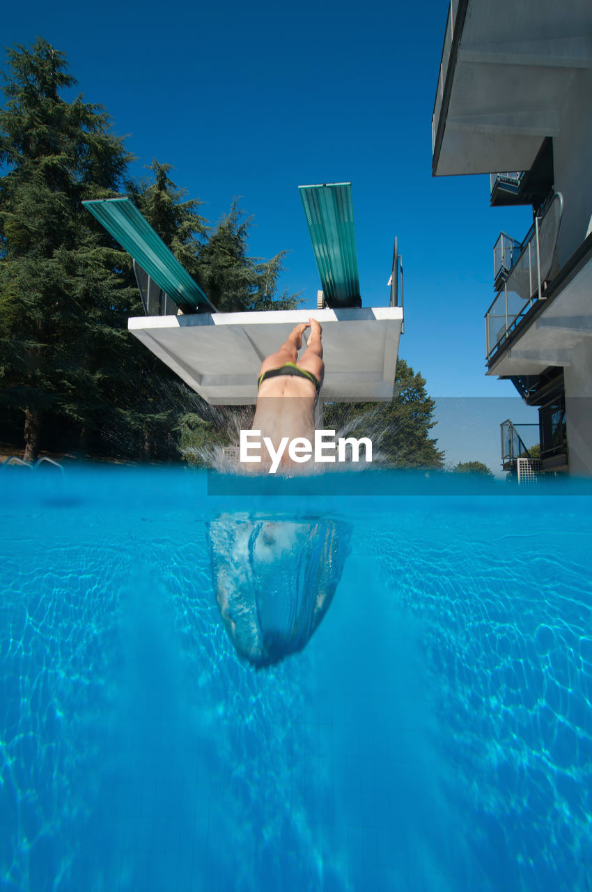 LOW SECTION OF MAN SWIMMING IN POOL AGAINST SEA