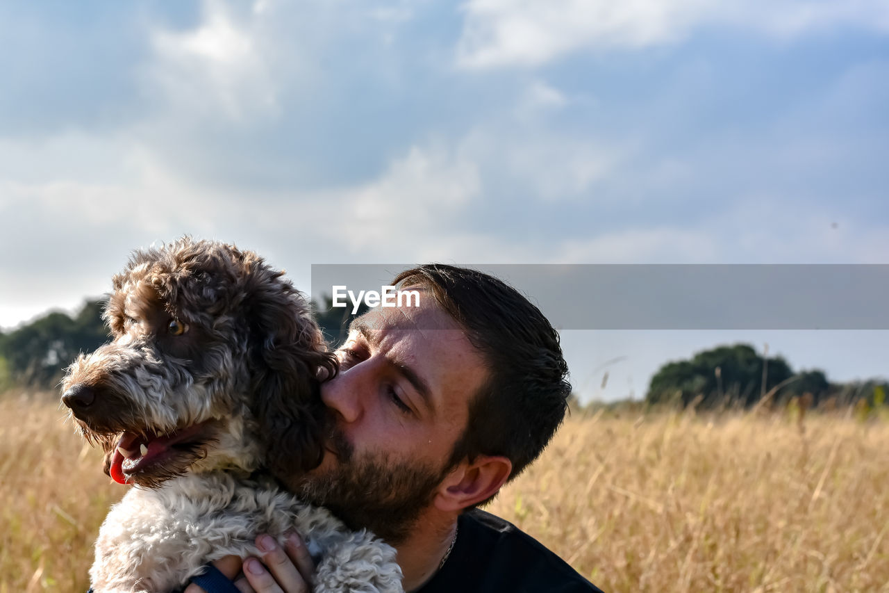 Man with dog on field against sky