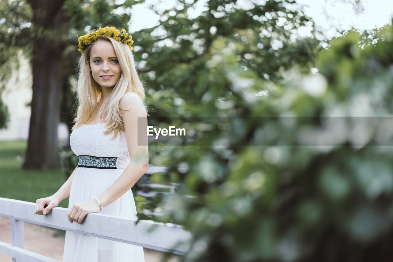 Portrait of young woman standing at park