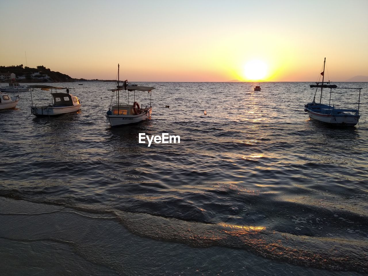 SAILBOATS MOORED ON SEA AGAINST SKY DURING SUNSET