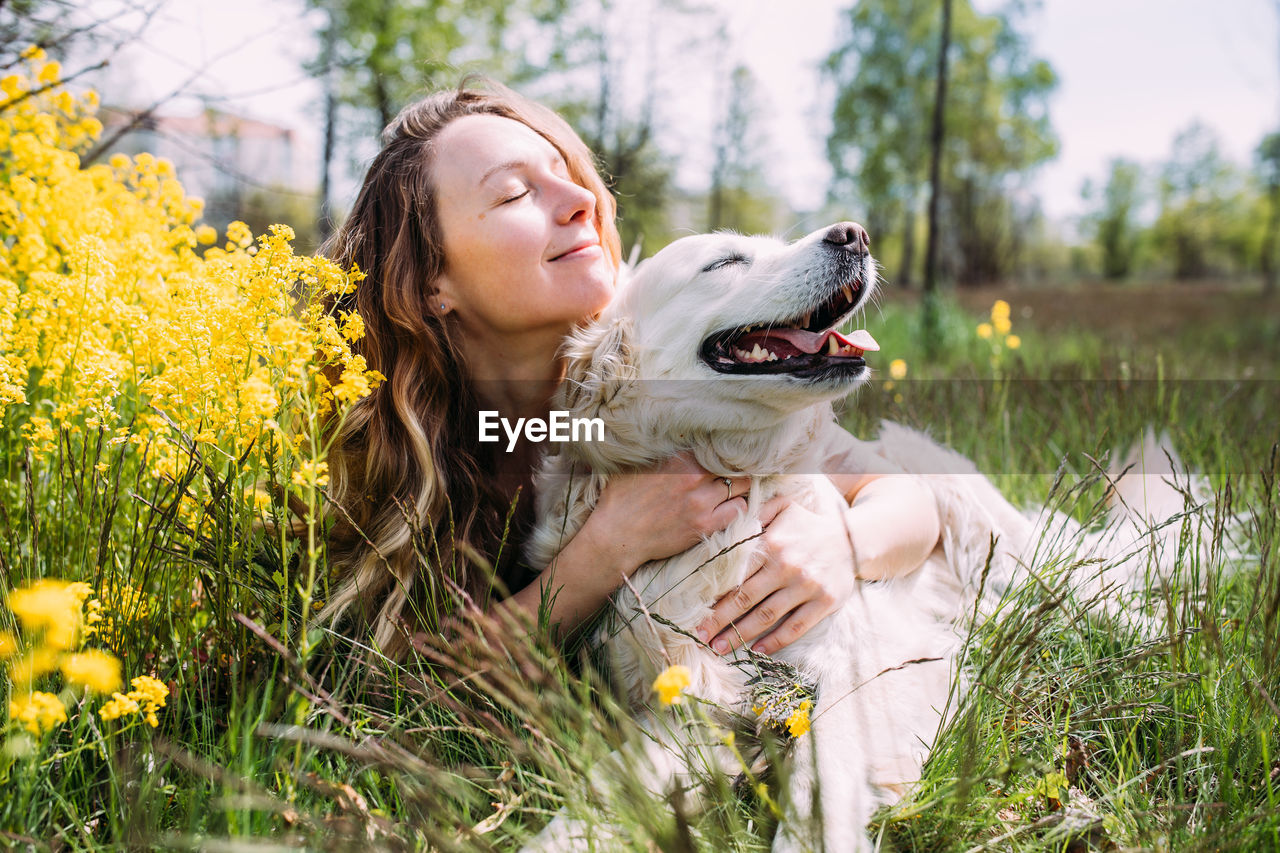 Young beautiful woman and her golden retriever dog having fun in summer