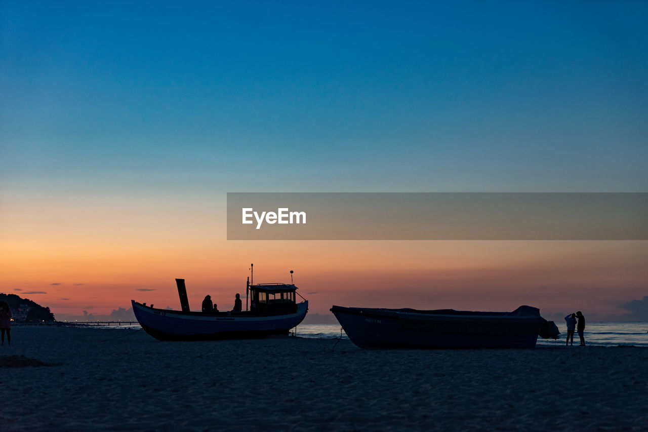 Boat moored on sea against sky during sunset