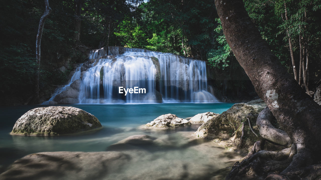 Scenic view of waterfall smooth flowing water in rainforest. erawan falls, kanchanaburi, thailand.