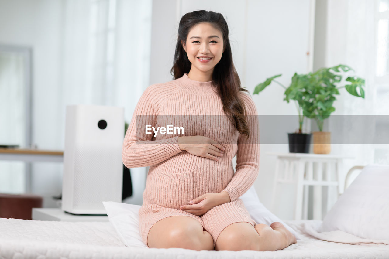 Portrait of smiling young woman sitting on bed