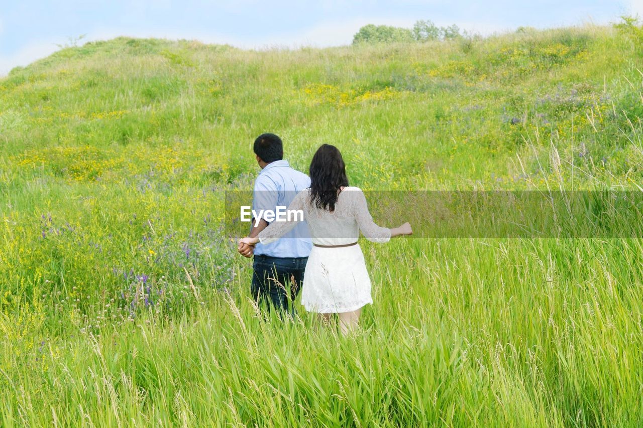 Rear view of man and woman on grassy field