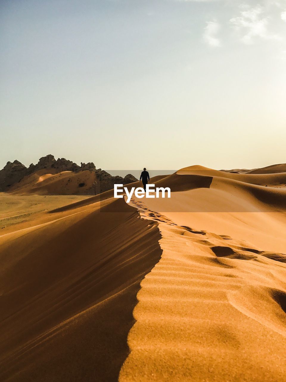 Man walking on desert against clear sky