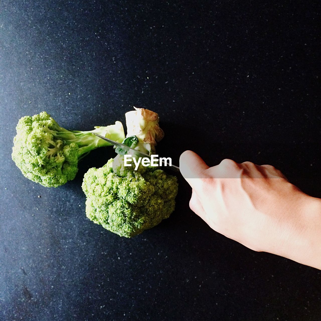 Cropped image of person chopping broccoli on table