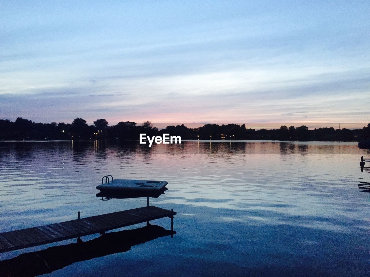 Scenic view of lake by silhouette trees against sky