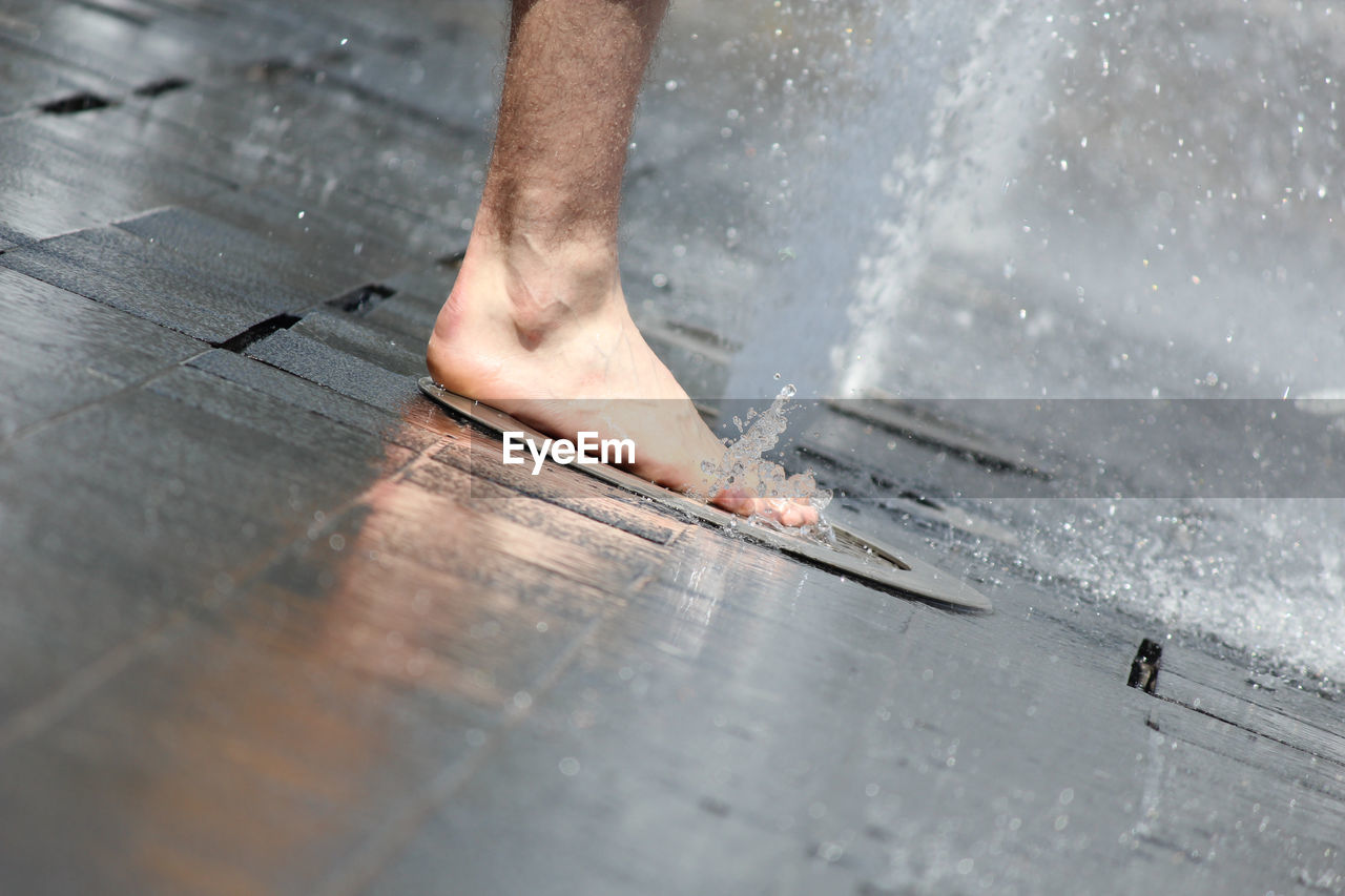 Low section of man stepping on fountain