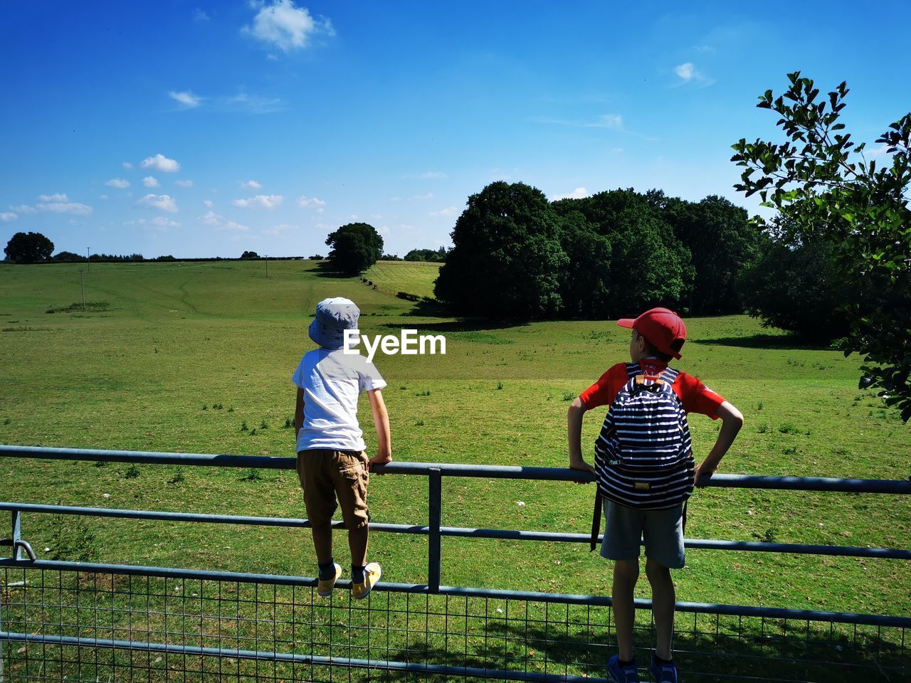 rear view, sky, plant, nature, two people, men, grass, child, full length, childhood, leisure activity, rural area, adult, tree, sports, togetherness, landscape, green, field, family, casual clothing, land, day, activity, outdoors, lifestyles, agriculture, environment, blue, women, cloud, person