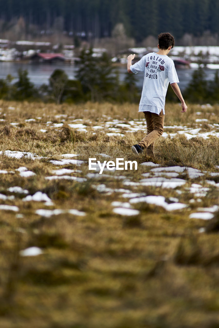 Rear view of boy walking on field