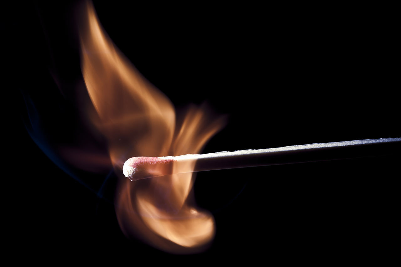 Close-up of burning candle against black background