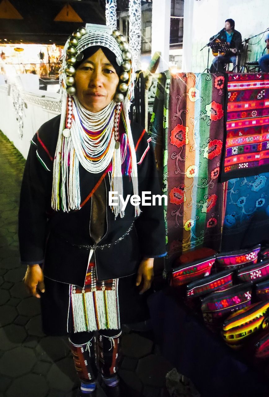 Portrait of woman in traditional clothing standing at market stall