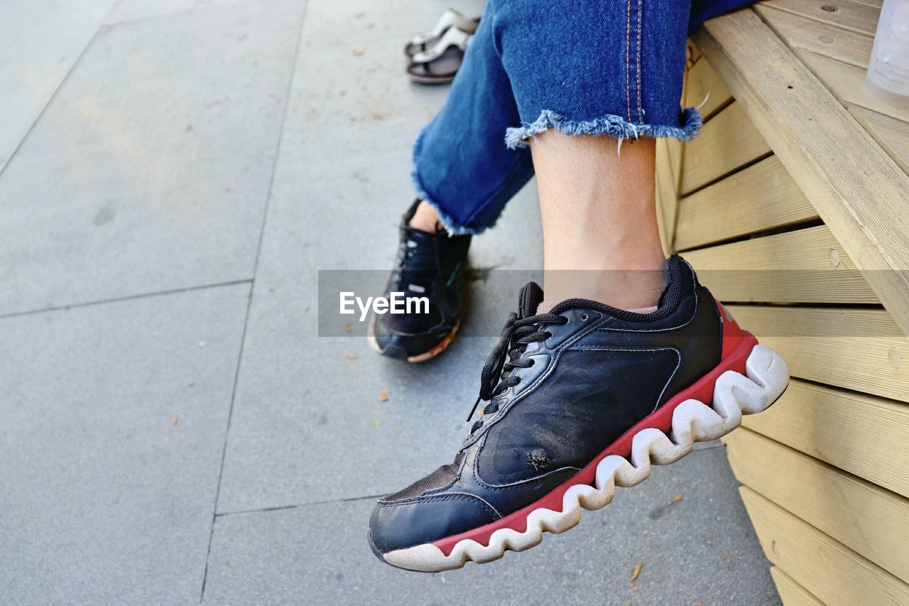 LOW SECTION OF WOMAN WEARING HIGH HEELS ON FOOTPATH