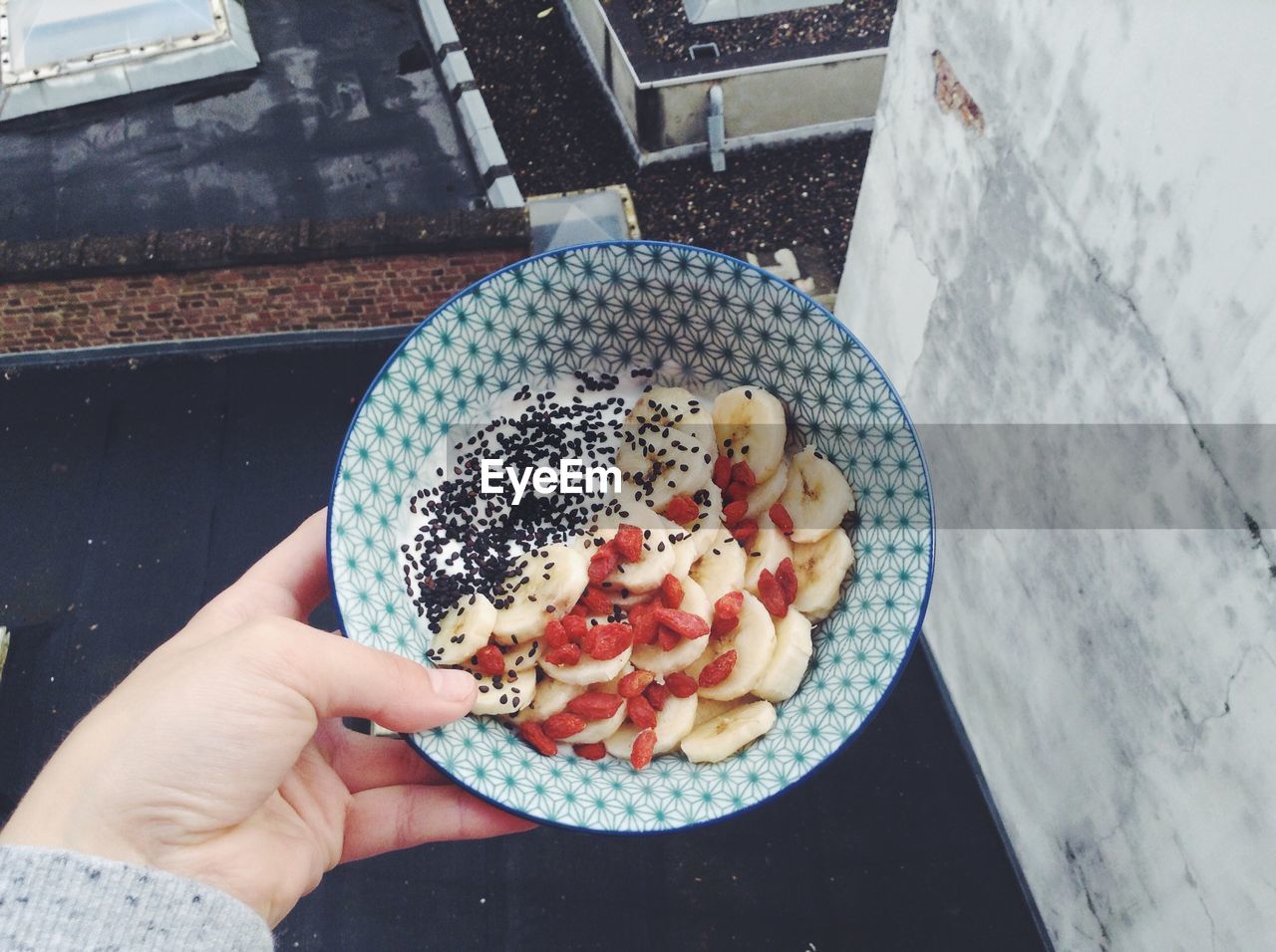 Cropped image of hand holding bowl of fruits