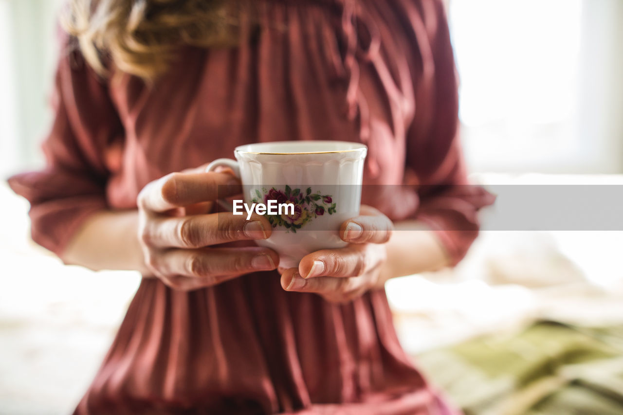 Midsection of woman drinking coffee in cup