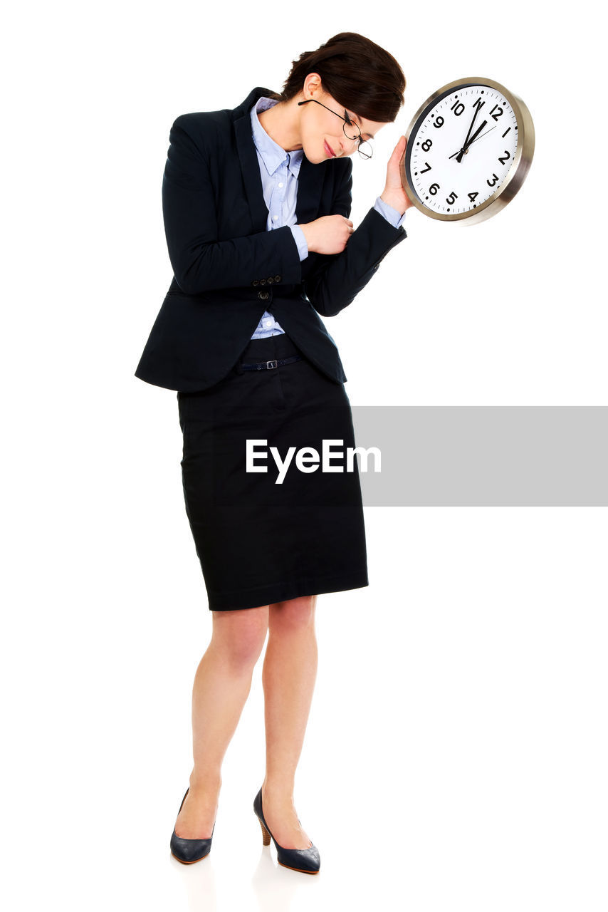 Full length of businesswoman holding clock against white background